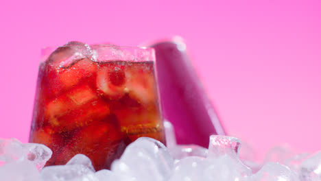 Nahaufnahme-Eines-Gekühlten-Kaltgetränks-Im-Glas,-Das-Aus-Der-Dose-Auf-Eiswürfel-Vor-Rosa-Hintergrund-Gegossen-Wurde-1